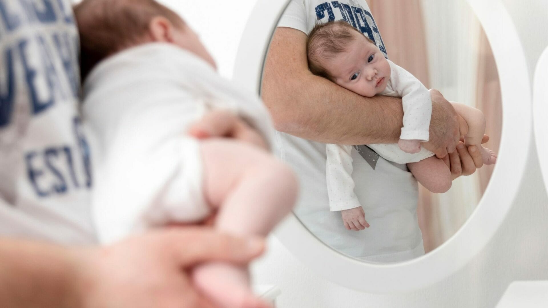 baby in mirror held by dad
